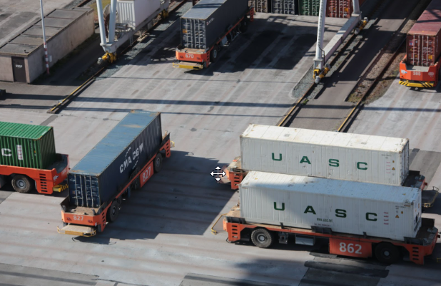 Två vita containrar staplade på varandra samt två släp som har varsin blå container ovanpå sig.
